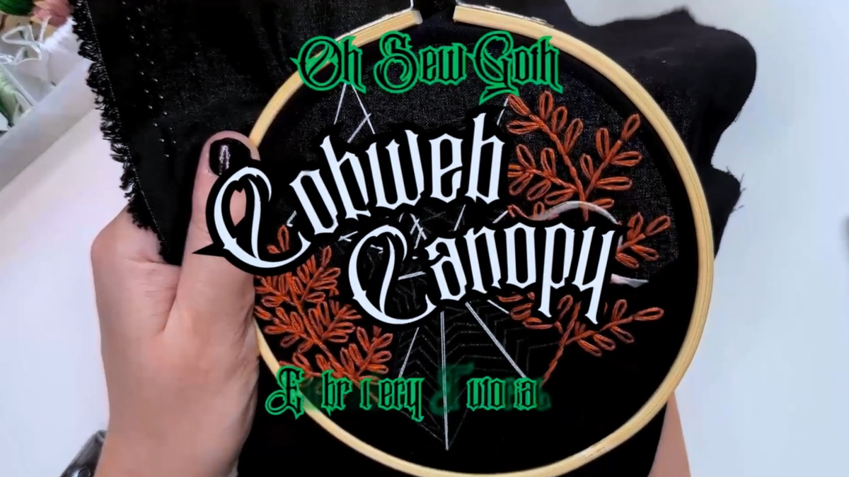 Load video: Full walk-through tutorial of Cobweb Canopy, a new pattern by Oh Sew Goth which includes two burnt orange plants created with stem stitch and lazy daisy stitch and joined by a cobweb made with straight stitch and fly stitch.